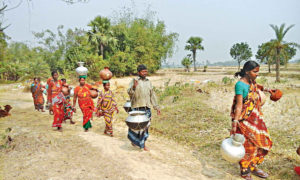 People carry drinking water to their home in Rajshahi’s Tanone upazila. With the groundwater level dropping and rainfall decreasing alarmingly over the years, residents of the country’s Barind region have to toil hard to fetch water from deep tube wells as far as kilometres away from their homes. The photo was taken recently. Photo: Collected
